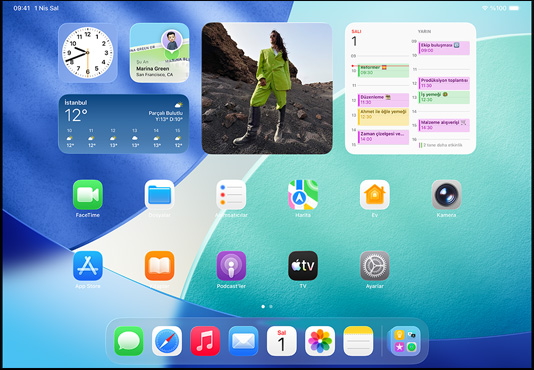 iPad, üç model, yatay pozisyonda, ortadaki model diğer ikisinin önünde duruyor, Apple Pencil ortadaki modelin üstüne manyetik olarak yapışmış, ortadaki ekranda Liquid Glass efektli renkli uygulama simgelerinin yer aldığı Ana Ekran görünüyor, soldaki ekranda Önizleme uygulaması görünüyor, sağdaki ekranda ise yelpaze şeklinde açılarak Dock’tan yukarı doğru çıkan dosyaların bulunduğu Ana Ekran görünüyor