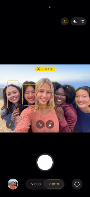 iPhone 17 Pro, voorkant, op het scherm de feature Middelpunt voor foto’s, toont hoe je een selfie van een groep mensen maakt, hun gezichten in kaders